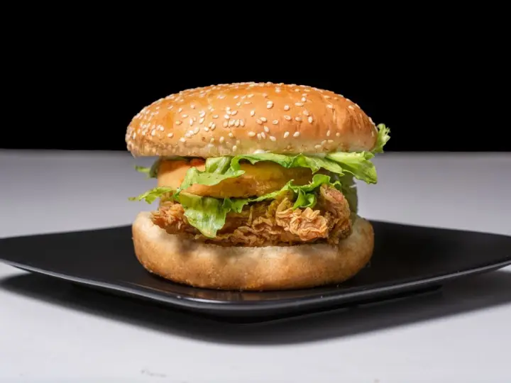 Crispy chicken sandwich with lettuce on a dark plate