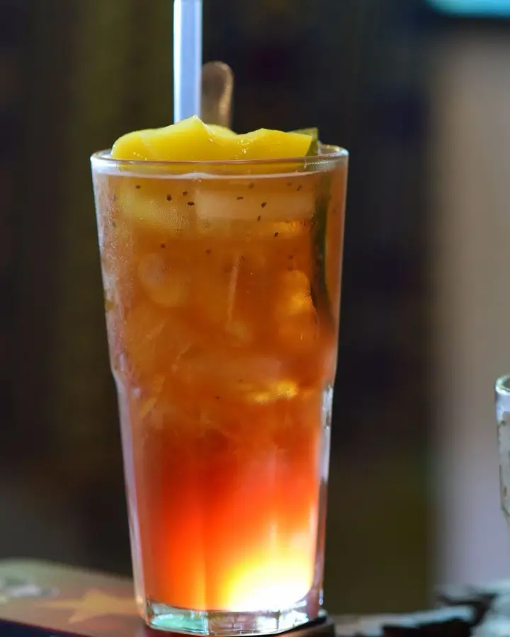 Tall glass of iced peach tea with a straw